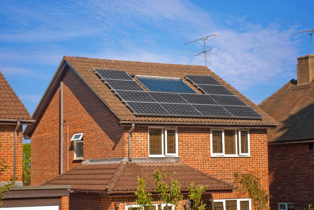 Brick house with rooftop solar panels and a solar water heater on a tiled roof